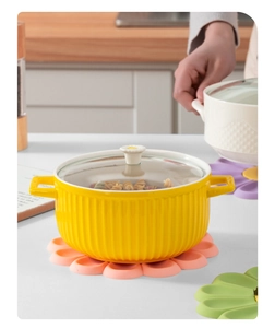 Close-up of pink flower silicone trivet under a yellow ceramic pot with floral handle