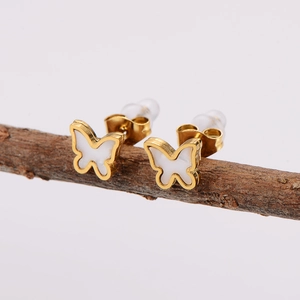 Elegant gold butterfly stud earrings with white inlay displayed on a natural wooden branch