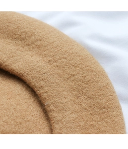 Close-up of brown wool beret showing premium fabric texture and fine edge stitching