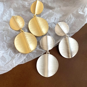 Detailed view of layered circular brushed metal earrings in gold and silver finishes