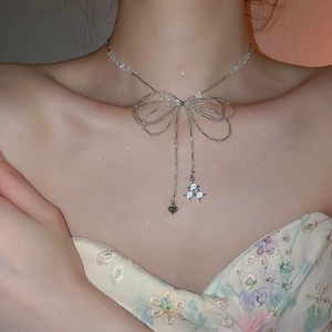 Detail of beaded bow necklace with heart pendant and light stones on model's neckline