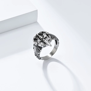 Detailed close-up of gothic skull and dagger ring with vintage silver finish on white stand