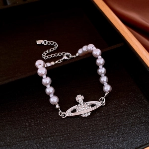 Detailed macro shot of a white pearl bracelet with a sparkling crystal orb saturn pendant