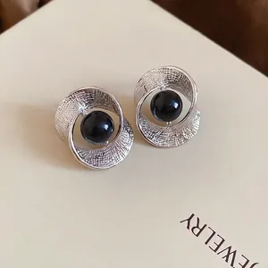 Minimalistische silberne gedrehte Ohrringe mit schwarzer Perle auf Schmuckbox