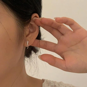 Close-up of elegant long silver knot earrings showing the minimalist metallic finish