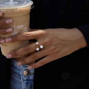 Elegance on display: three-stone staggered gold zircon ring worn while holding coffee cup