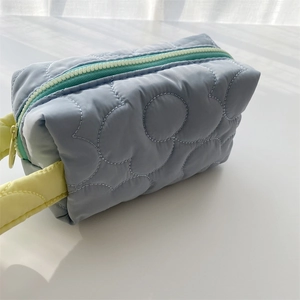 Close-up of quilted floral makeup bag with yellow strap and contrast zipper detail