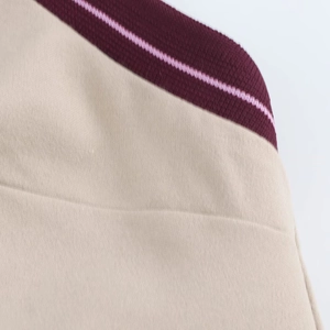 Dettaglio del tessuto in maglia a coste beige con bordo del colletto a righe bordeaux e rosa