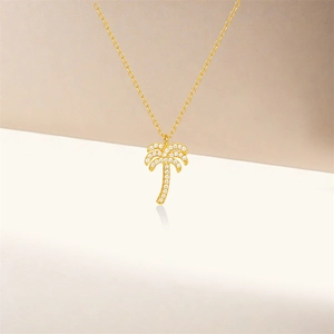 Detail of 18K gold palm tree pendant with cubic zirconia stones on thin chain