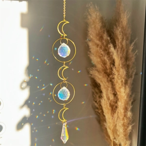 Golden moon suncatcher with clear crystals casting colorful light on a neutral wall