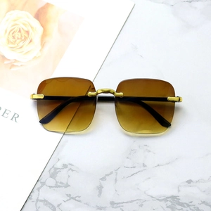 Frameless oversized sunglasses with gradient brown lenses and gold metal frame on marble