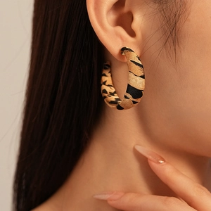Close-up of model wearing C-shaped leopard print fabric earrings in a vintage style