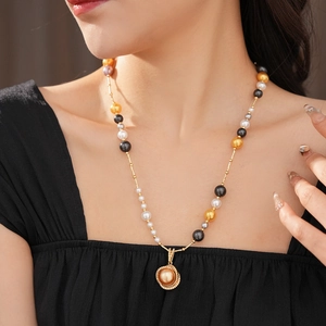 Detail of a luxury pearl necklace featuring multi-colored pearls and gold zircon pendant