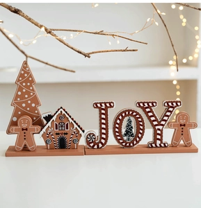Detail of JOY Christmas wooden gingerbread house and tree desktop decor with warm lights