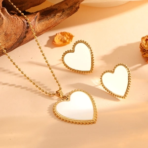 Macro shot of gold-plated heart-shaped jewelry set with white shell inlay and bead trim