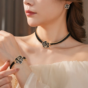 Macro shot of camellia flower jewelry set featuring black weave and crystal details