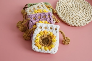 Flat lay of colorful handmade sunflower knit drawstring bags in white, purple and beige