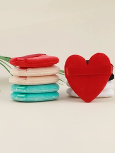 Macro shot of colorful velvet heart and round makeup puffs with soft ribbon handles