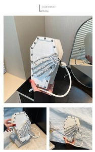 Detailed macro of white coffin-shaped bag featuring skull texture and bone hand charm