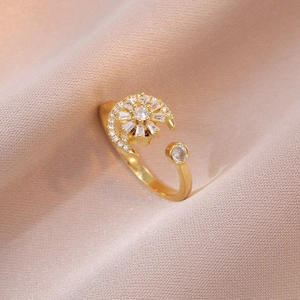 Rotating golden moon and sunflower ring with zircon stones on silk background