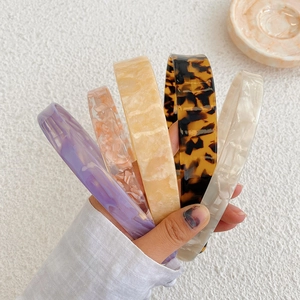Hand holding assorted marble and tortoiseshell cellulose acetate headbands for women