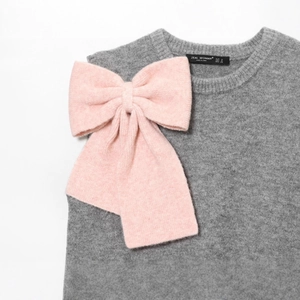 Gilet in maglia grigia da donna con un grande fiocco rosa decorativo in tessuto morbido