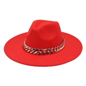 Detail of red wide brim fedora hat featuring a chunky gold chain link accent
