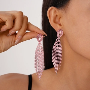 Detailed close-up of pink rhinestone tassel earrings elegantly worn by a female model