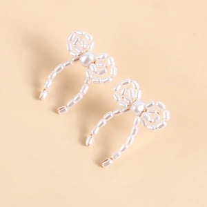 Close-up of handmade faux pearl bow earrings featuring intricate woven beadwork detail
