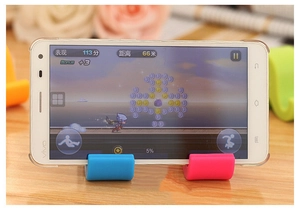 Close-up of colorful elephant desk phone stands supporting a smartphone on wooden surface