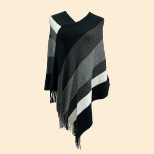 Detail of V-neck knitted poncho featuring grey gradient stripes and tassel hem decorations