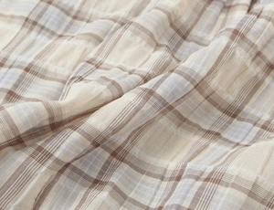Macro shot of plaid woven fabric with beige brown and light blue textured checkered pattern