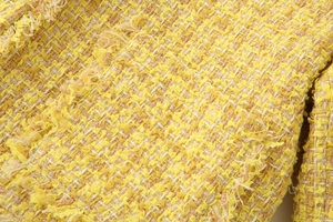 Macro shot of yellow tweed fabric with interwoven white and gold metallic threads