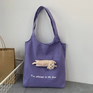 Detail of purple canvas tote bag featuring a 3D plush cat doll and white embroidery