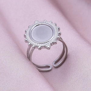 Detailed macro view of an adjustable stainless steel oval sunburst ring on pink silk