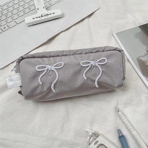 Macro detail of the gray-purple fabric pencil case with white bow embroidery and zipper