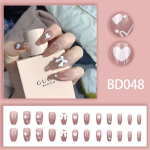 Detail of pink press-on nails with 3D bows, pearls, and heart designs in trapezoid shape