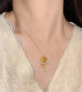 Close-up of a gold rocking horse necklace with zircon stones on a female model
