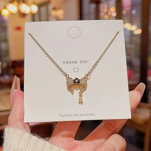 Detail of gold necklace with crystal bow, black camellia, and teardrop pendant charm