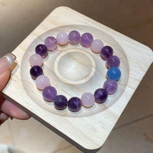 Detailed view of colorful natural crystal beads on a wooden tray in purple and pink