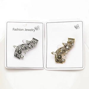 Detail view of musical note brooches in gold and silver finish with sparkling rhinestones