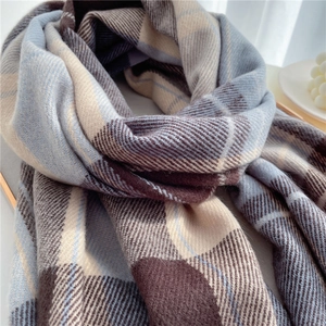 Detailed view of soft blue and beige plaid scarf texture with stylish fringe finish