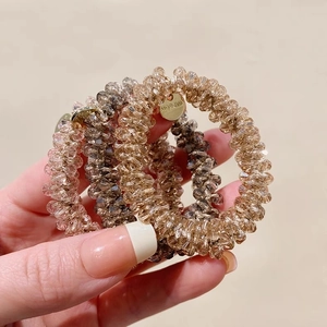 Three crystal beaded hair ties in pink and brown with elegant metal pendant charms