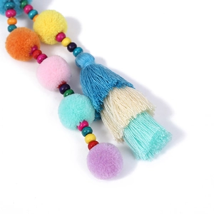 Dettaglio macro del portachiavi bohémien con pompon colorati, perline in legno e nappa in seta