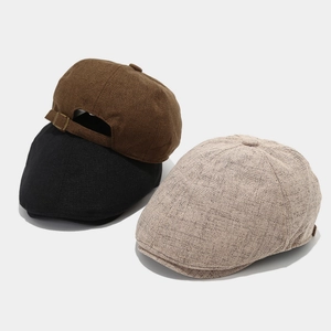 Close-up of retro cotton linen newsboy caps in black, brown and beige with metal buckle