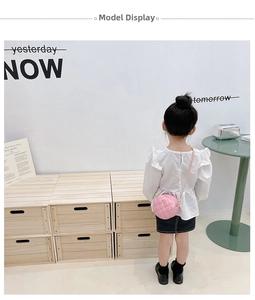 Rear view of a girl wearing a pink quilted round crossbody bag with a gold heart clasp