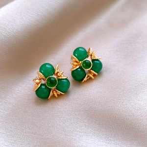 Gros plan de boucles d'oreilles vintage dorées avec perles vertes sur soie