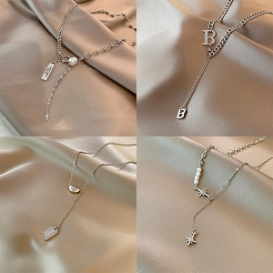 Minimalist titanium steel necklaces with star, pearl, and letter pendants on silk fabric