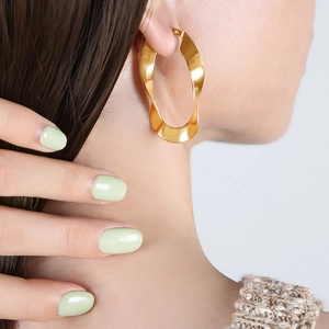 Fashionable gold twisted U-shaped titanium steel hoop earrings for women shown on model