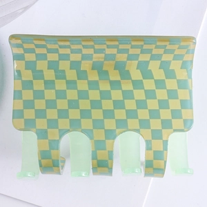 Close-up of a checkered hair claw clip in yellow and green acetate on white background